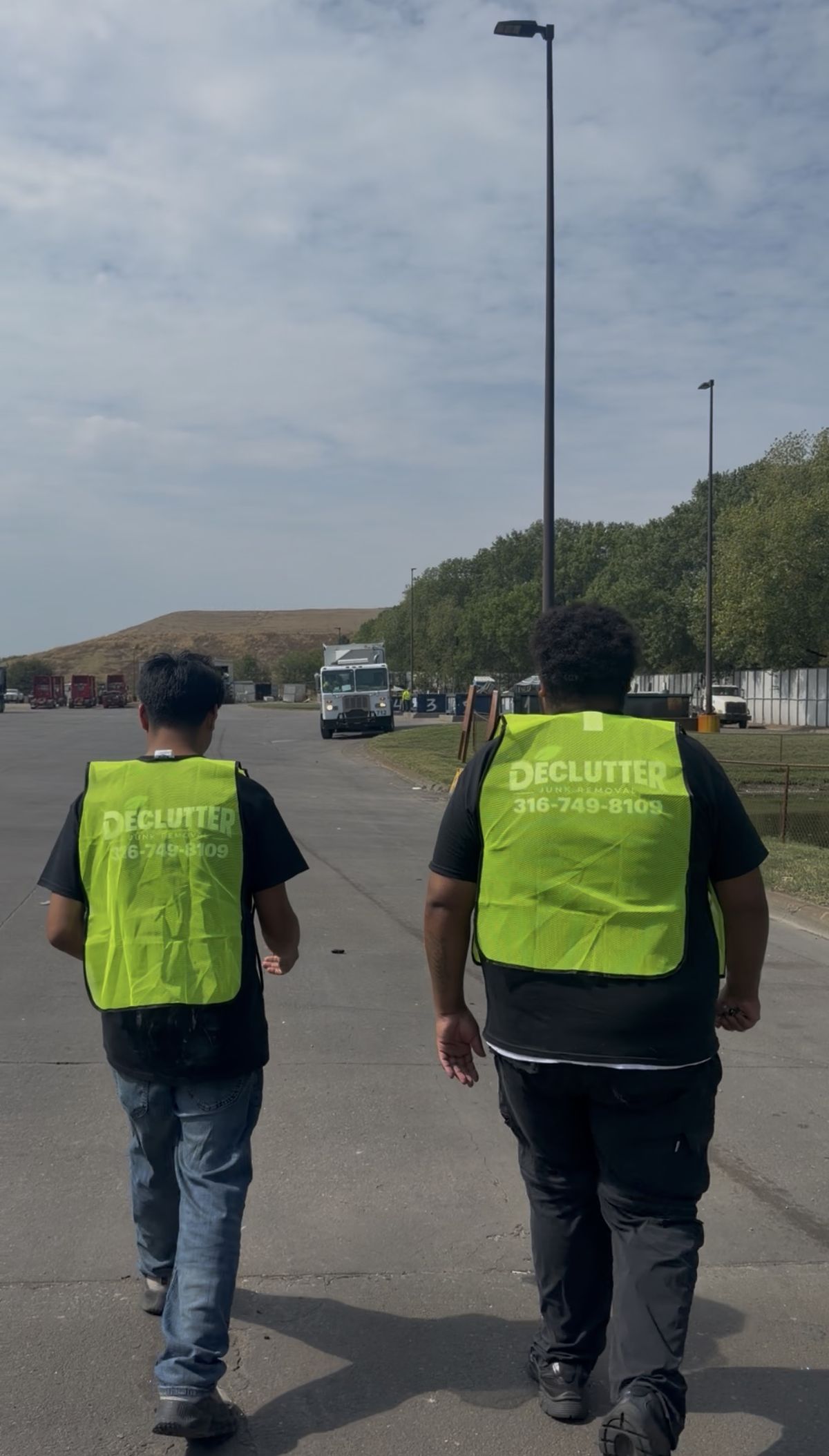 Two Declutter crew members in branded safety vests at the transfer station